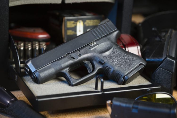 Used Glock Pistol Sitting On Desk With Bullets Next To It